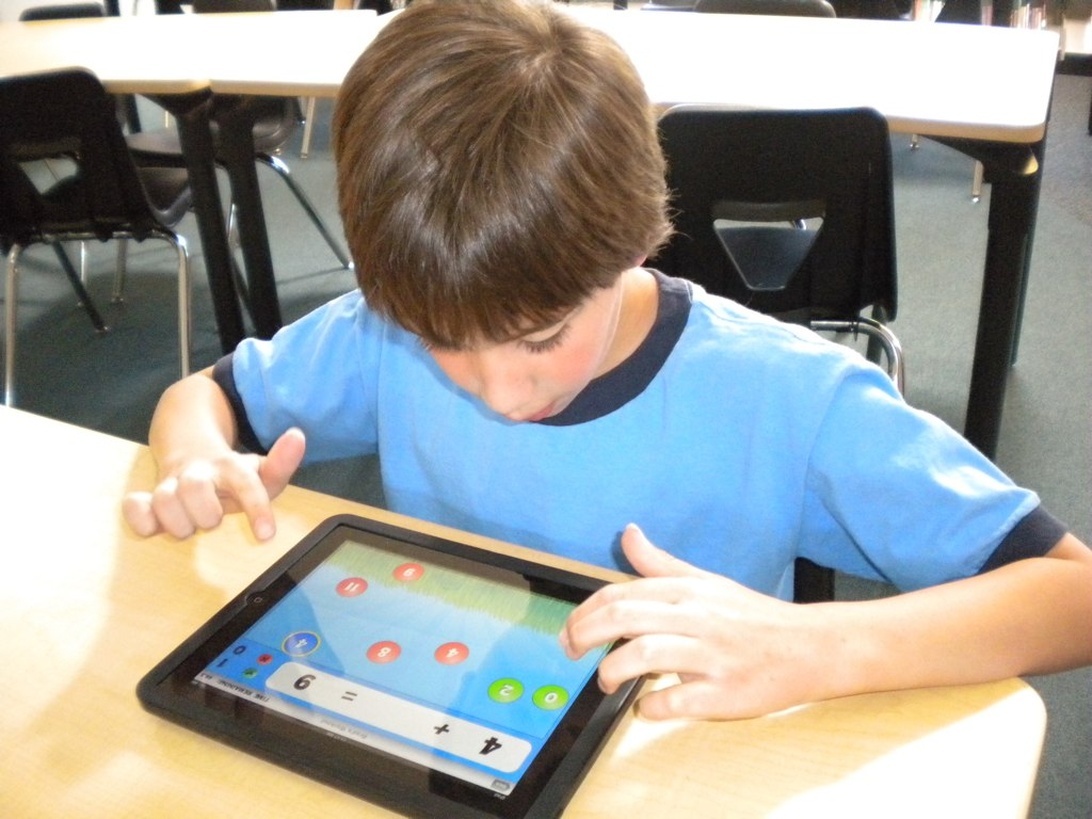 Ein kleiner Junge konzentriert sich auf ein Tablet in einem Klassenzimmer.