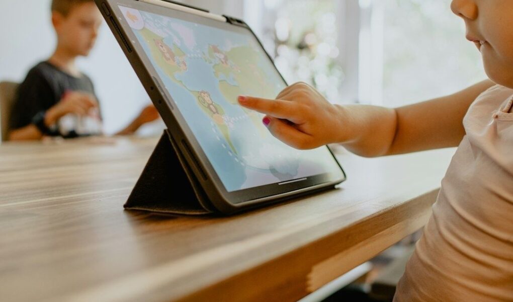 Kind tippt auf ein Tablet mit einer bunten Lernspiel-App