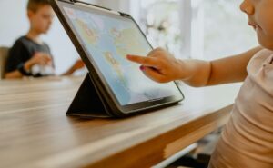 Kind tippt auf ein Tablet mit einer bunten Lernspiel-App