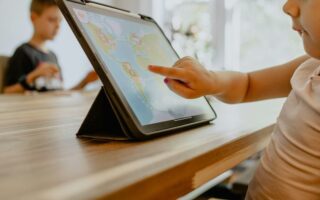 Kind tippt auf ein Tablet mit einer bunten Lernspiel-App