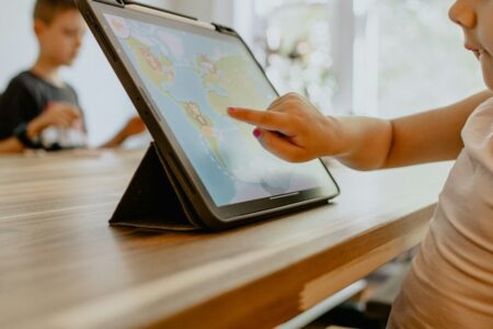 Kind tippt auf ein Tablet mit einer bunten Lernspiel-App