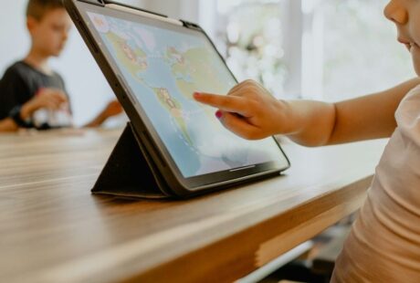 Kind tippt auf ein Tablet mit einer bunten Lernspiel-App