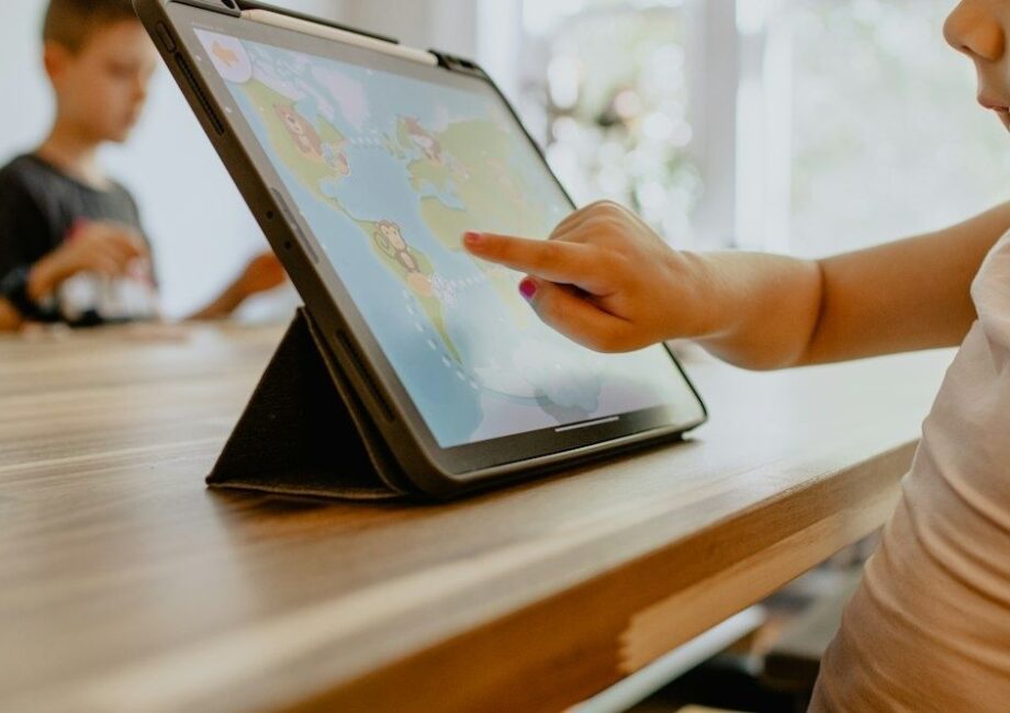 Kind tippt auf ein Tablet mit einer bunten Lernspiel-App